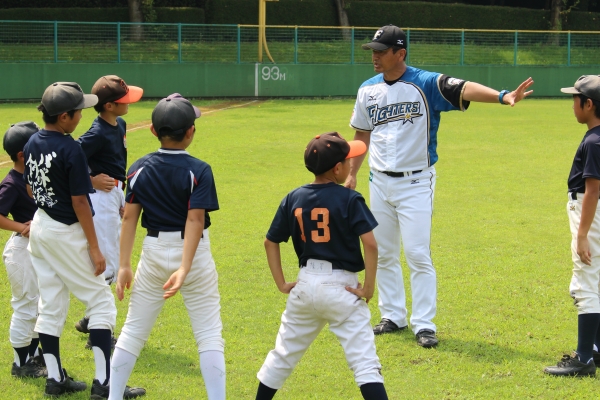 コーチに指導を受けている少年野球チームの選手たち